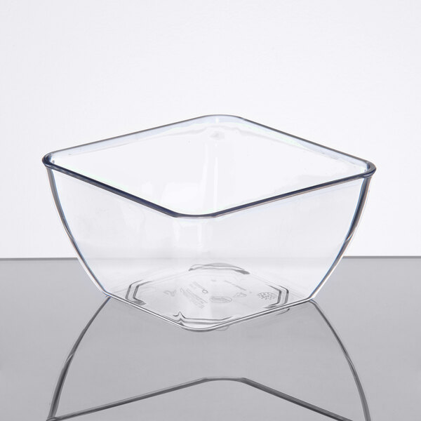 A white table with a clear square SAN plastic bowl filled with food.