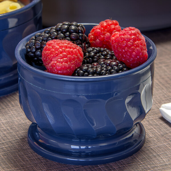 A Dinex dark blue insulated bowl with a bowl of blackberries on a table.