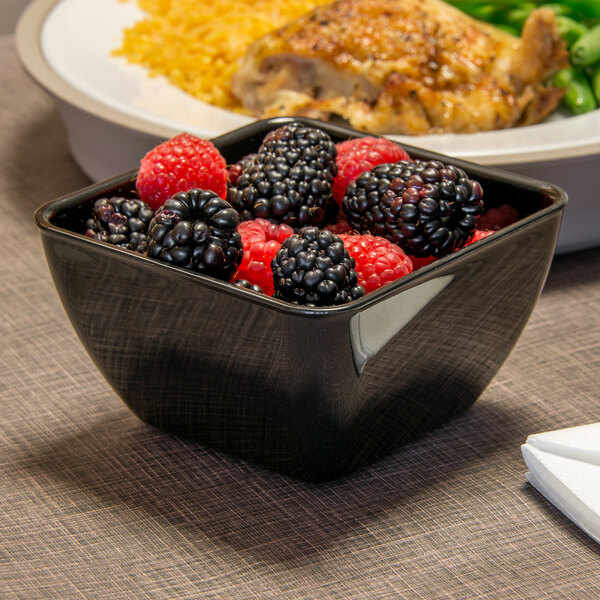 A black Dinex SAN plastic bowl filled with blackberries and raspberries.