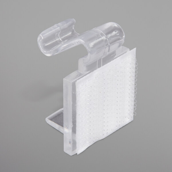 A clear plastic Snap Drape table skirt clip with a white strip.