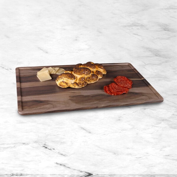 An Elite Global Solutions faux hickory wood melamine serving board with food on it on a counter.