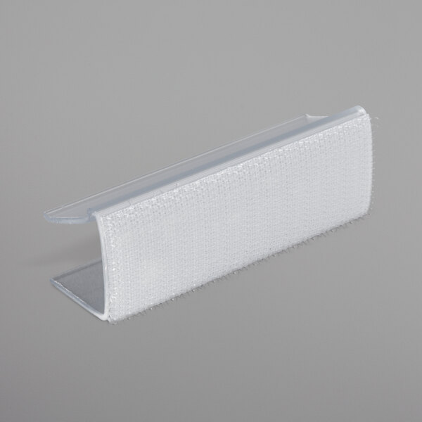 A white plastic Snap Drape table skirt clip with a clear plastic strip.