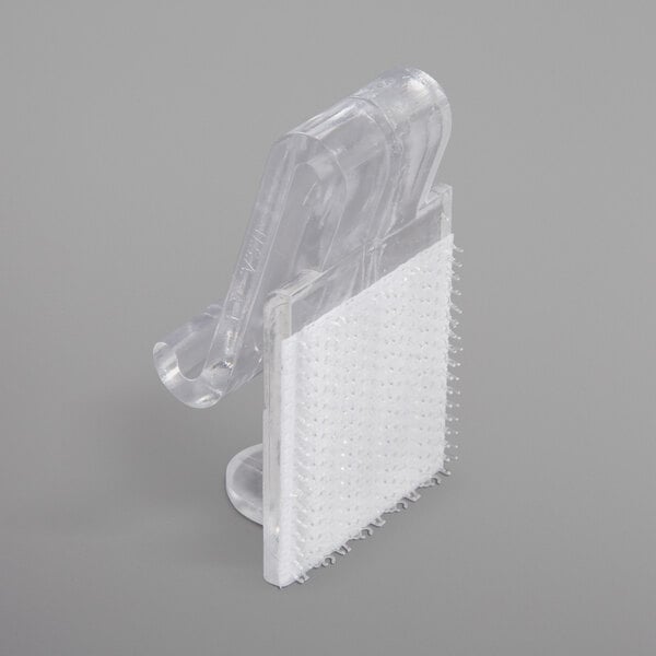 A close-up of a clear plastic Snap Drape table skirt clip with a hook and loop attachment.
