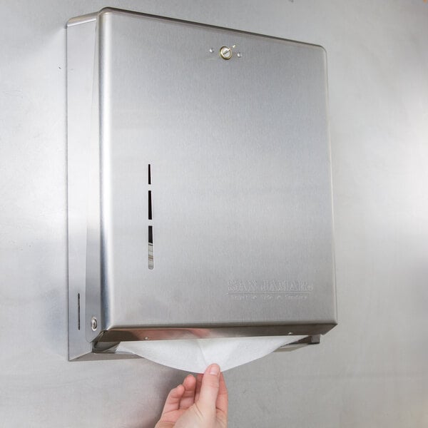 A hand pulling a paper towel out of a San Jamar stainless steel paper towel dispenser.