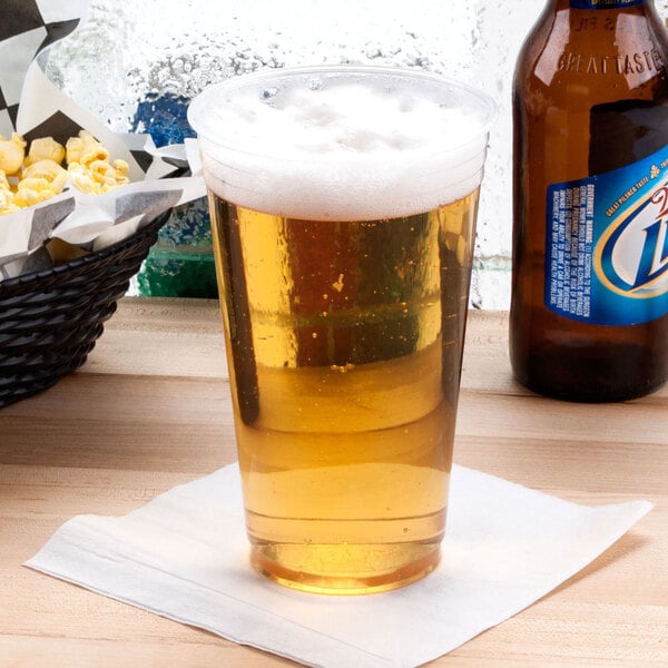 A Dart ClearPro plastic cup filled with beer on a table.