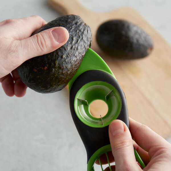 A person using an OXO 3-in-1 avocado tool to cut and pit an avocado.