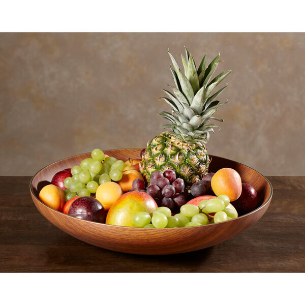 A GET faux wood bowl filled with fruit on a table.
