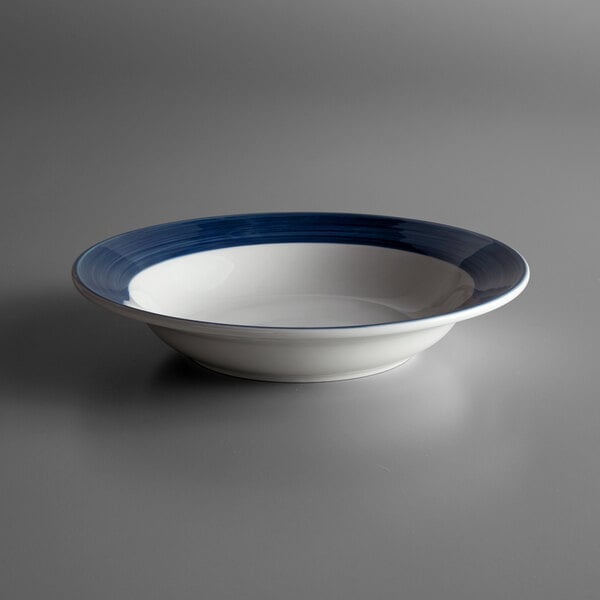 A close up of a Libbey Lunar Bright White Porcelain deep rim bowl with a steel blue band.