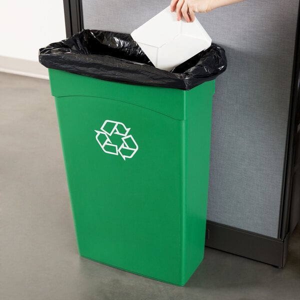 A hand putting white paper into a green Continental wall hugger recycle bin.