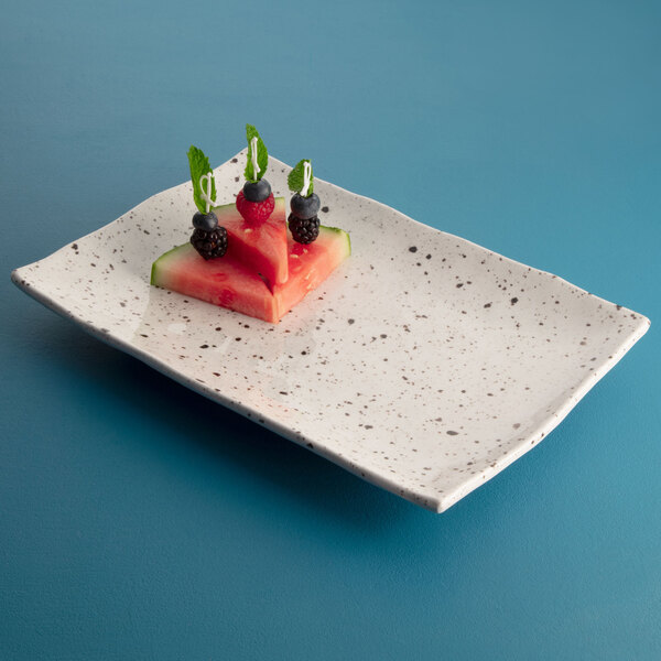 A rectangular chocolate chip melamine plate with watermelon slices and berries on it.