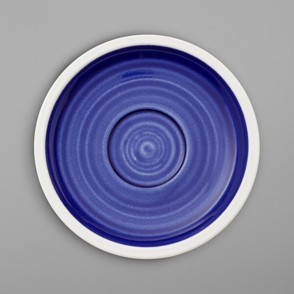 A white porcelain saucer with a blue spiral design on the border.