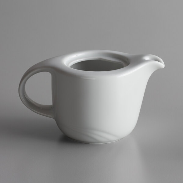 A white teapot with a handle.