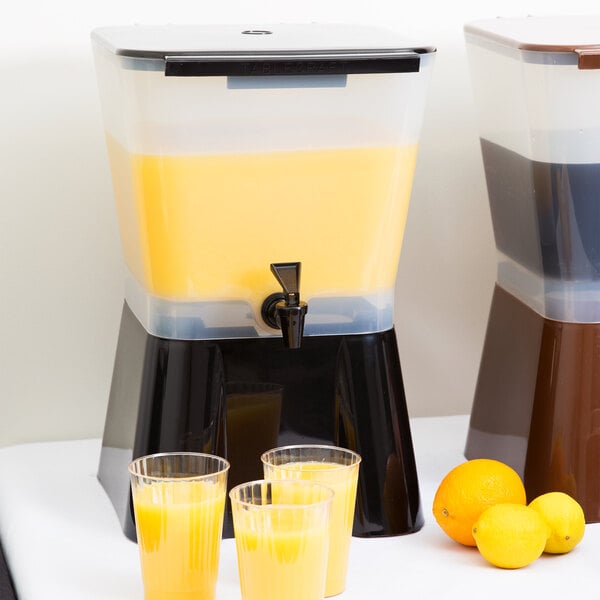 A Tablecraft black plastic beverage dispenser with a group of glasses of orange juice.