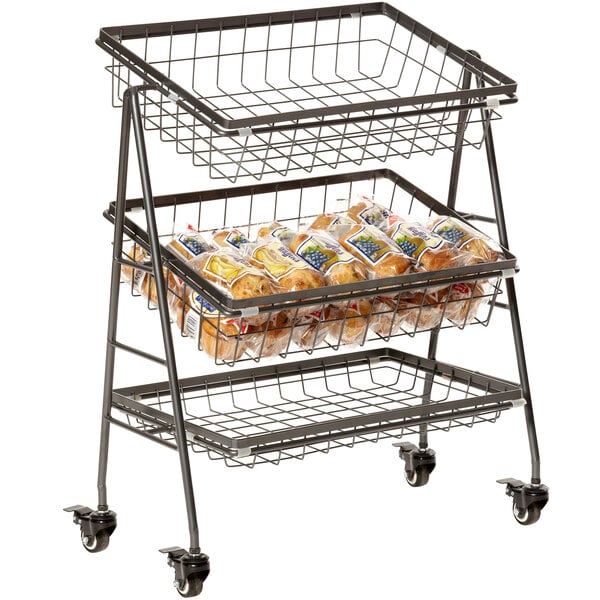 A metal rectangular three tier mobile merchandiser stand with wire baskets on wheels filled with food.