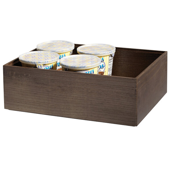 A wooden box with four containers of yogurt displayed on a table.