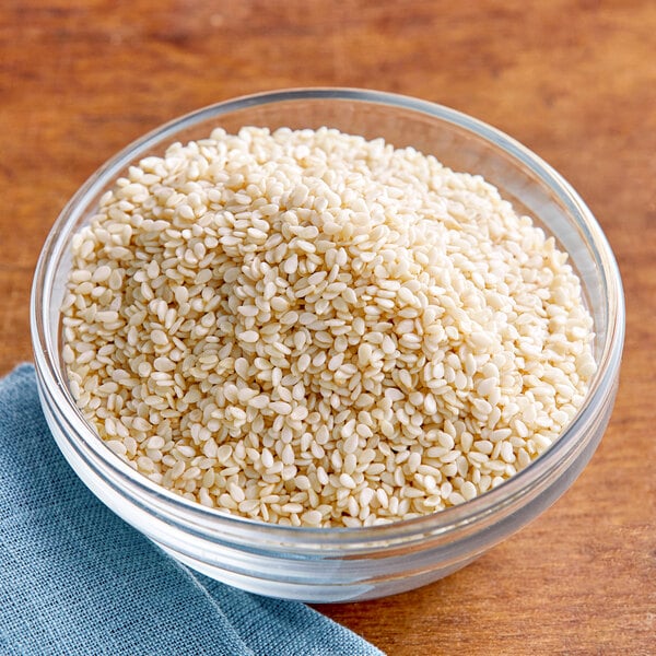 A bowl of white sesame seeds on a table.