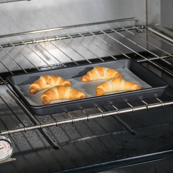 A Baker's Mark non-stick aluminum sheet pan with croissants on it.