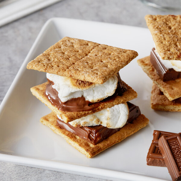 A plate of three s'mores with Nabisco Original Graham Crackers, chocolate, and marshmallows.
