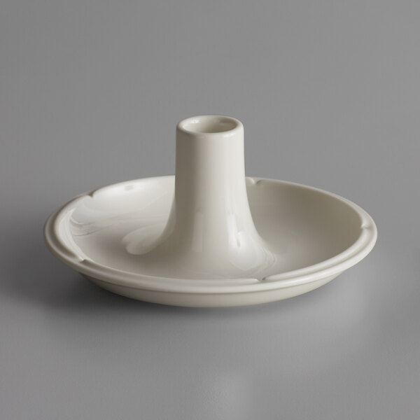 A white round RAK Porcelain candle holder on a gray surface.