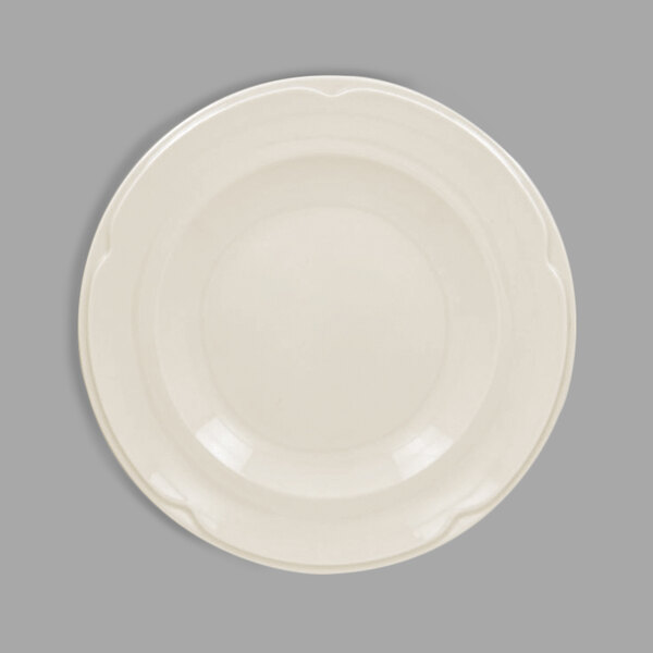 A close-up of a white RAK Porcelain flat plate with a scalloped edge.
