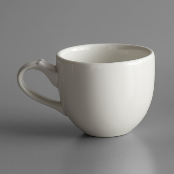 A RAK Porcelain ivory espresso cup with a handle on a gray surface.