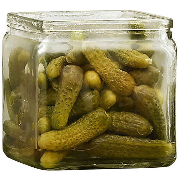 A glass jar filled with green and yellow pickles.