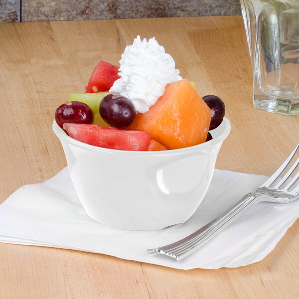 A white Thunder Group melamine bouillon cup filled with fruit and whipped cream with a fork.