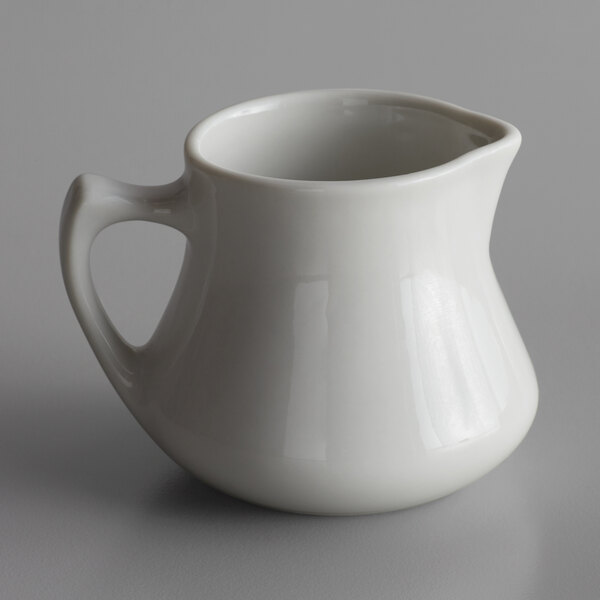 A Libbey white porcelain creamer with a handle.