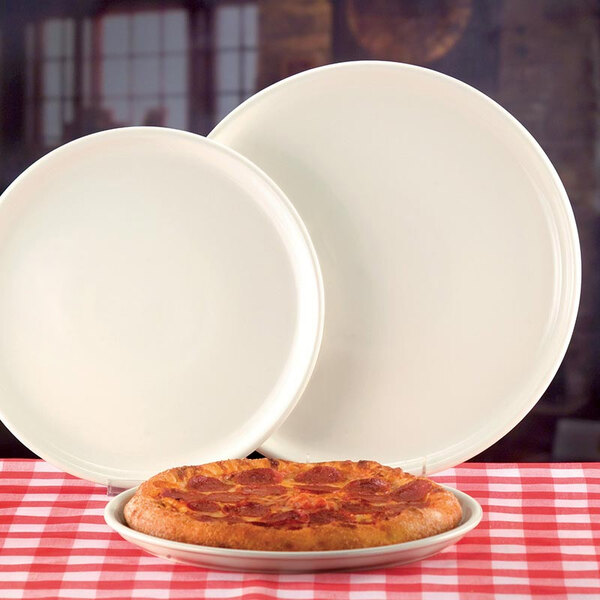 A pepperoni pizza on a Libbey white china pizza platter next to another pizza on a white china pizza platter.
