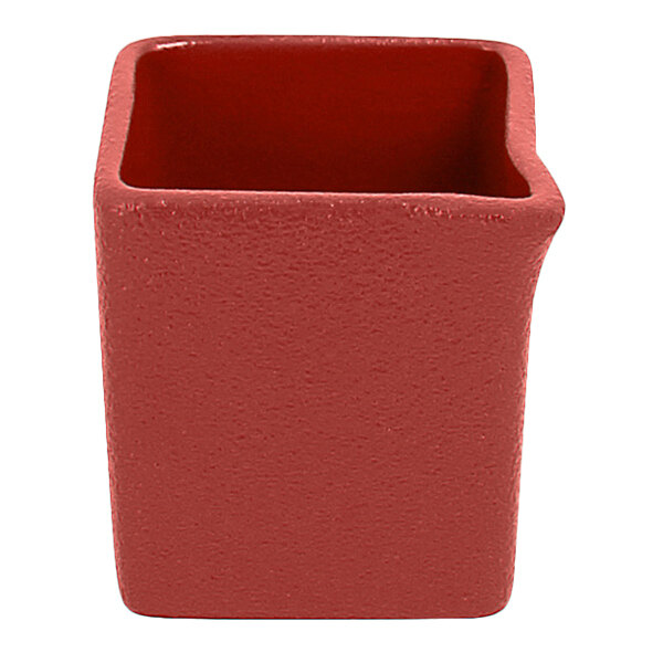 A red rectangular RAK Porcelain creamer with a curved edge and a hole.