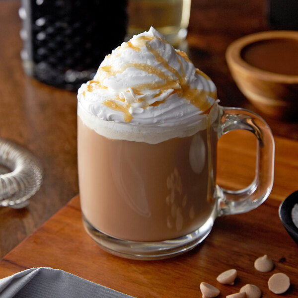 A glass mug of coffee with whipped cream and Monin Creme Caramel syrup.