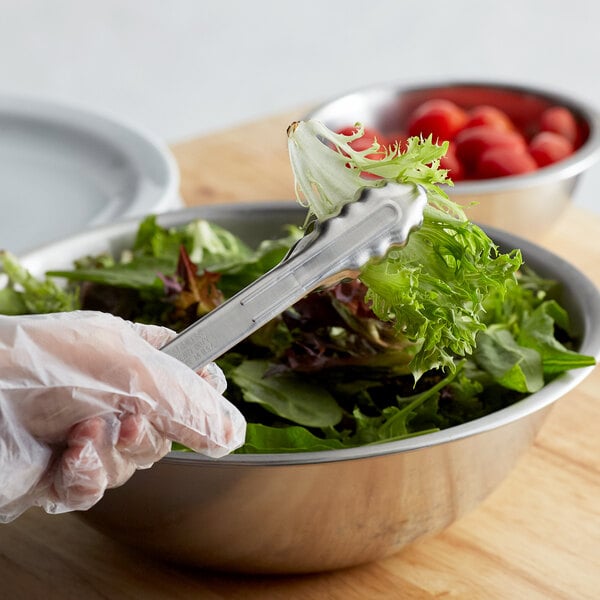 A person in gloves using Edlund Heavy-Duty Scallop Utility Tongs to serve salad.