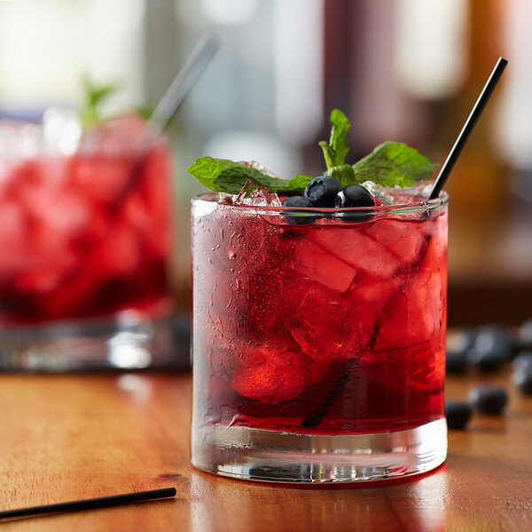 A glass of huckleberry cocktail with ice and berries.