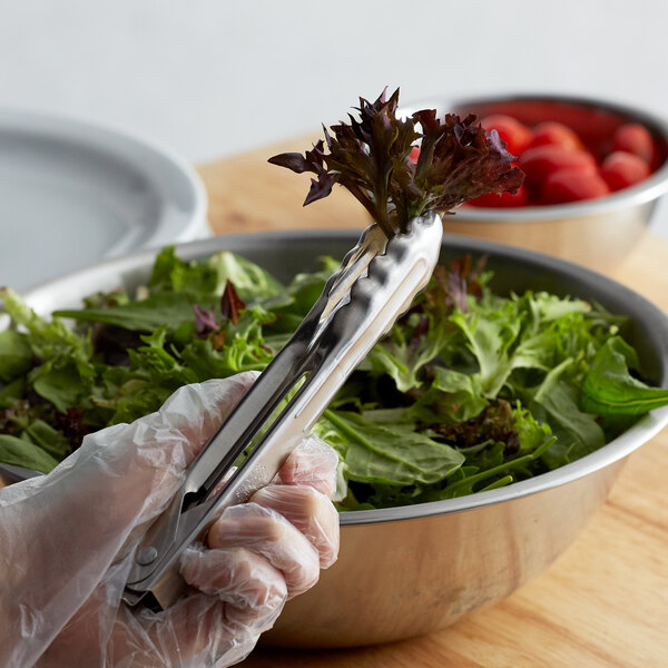 A person using Edlund heavy-duty scallop utility tongs to serve salad