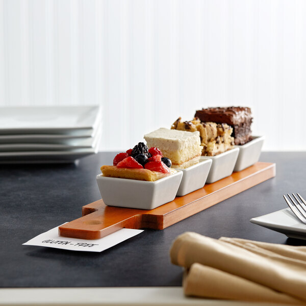 An Acopa dual-sided flight paddle with square tasting bowls on a table with dessert trays.
