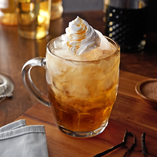 A glass of Monin vanilla creme flavoring syrup with whipped cream on top.