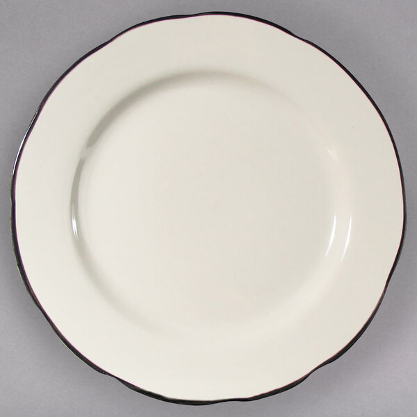 An ivory CAC scalloped edge china plate with a black rim.