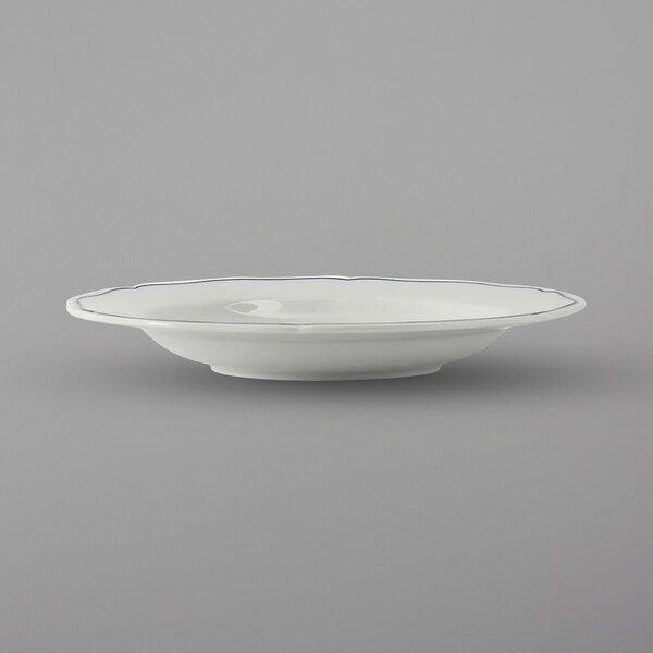 A Tuxton TuxTrendz pasta bowl with a white surface and scalloped edge with a blue band.