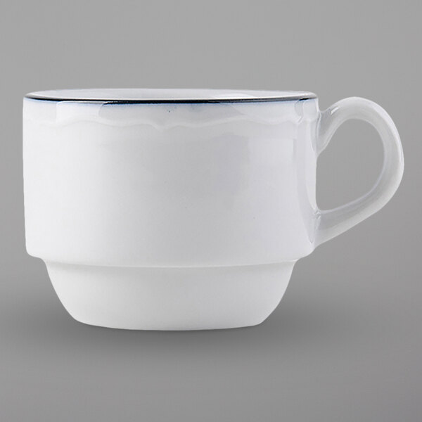 A white Tuxton espresso cup with a scalloped edge and a blue rim.