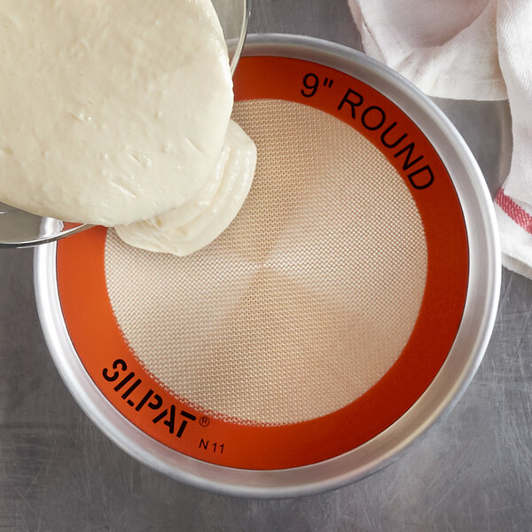 A white round dough being poured onto a round white Sasa Demarle SILPAT baking mat.
