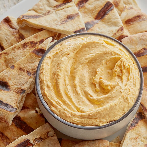 A bowl of Cheddar Horseradish cream cheese spread on a table with pita bread.
