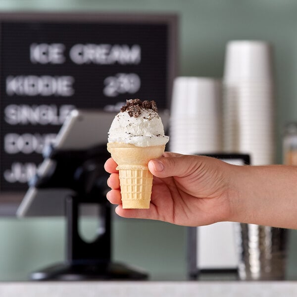 A hand holding a JOY flat bottom cake ice cream cone.