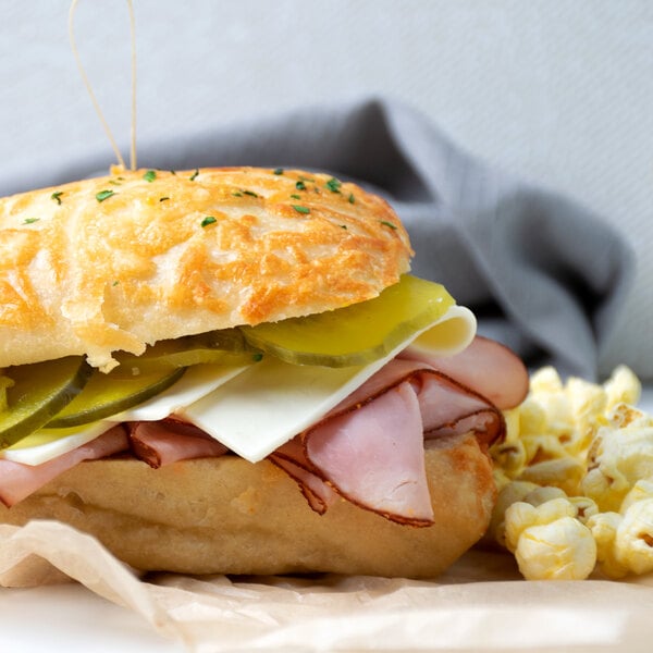 A sandwich with ham, cheese, and pickles on a white plate.