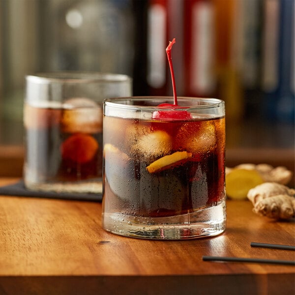 A glass of Monin ginger beer flavoring syrup with ice and a cherry.