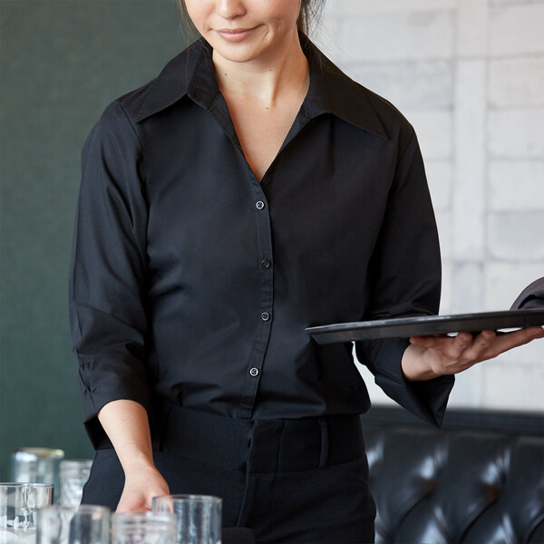 A woman wearing a Henry Segal black v-neck dress shirt holding a tray and a glass of water.