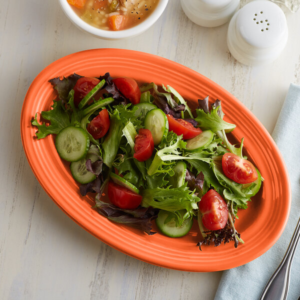 A Tuxton oval china platter with salad and tomatoes and cucumbers.