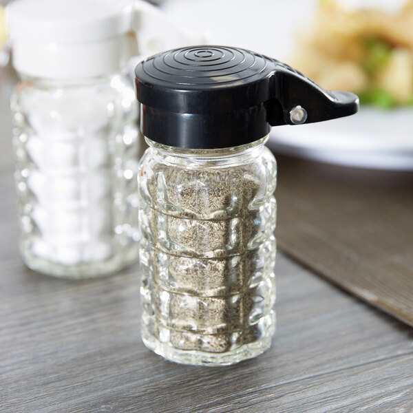 A Tablecraft glass shaker with a black lid and cap.
