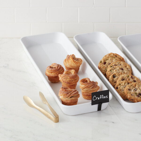 Two white American Metalcraft rectangular market trays filled with pastries and cookies.