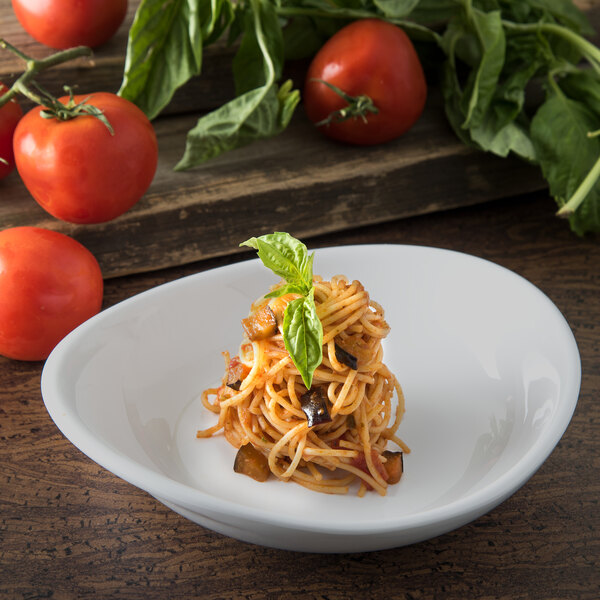 A Carlisle pasta plate with spaghetti topped with basil and tomatoes.