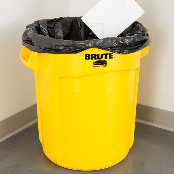 A yellow Rubbermaid BRUTE trash can with a black liner inside.